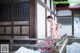 A woman in a kimono sitting on a wooden bench in the snow.