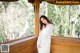 A woman in a white dress standing on a porch.