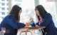 A couple of young women sitting at a desk in a classroom.