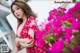 A woman in a red dress standing in front of pink flowers.